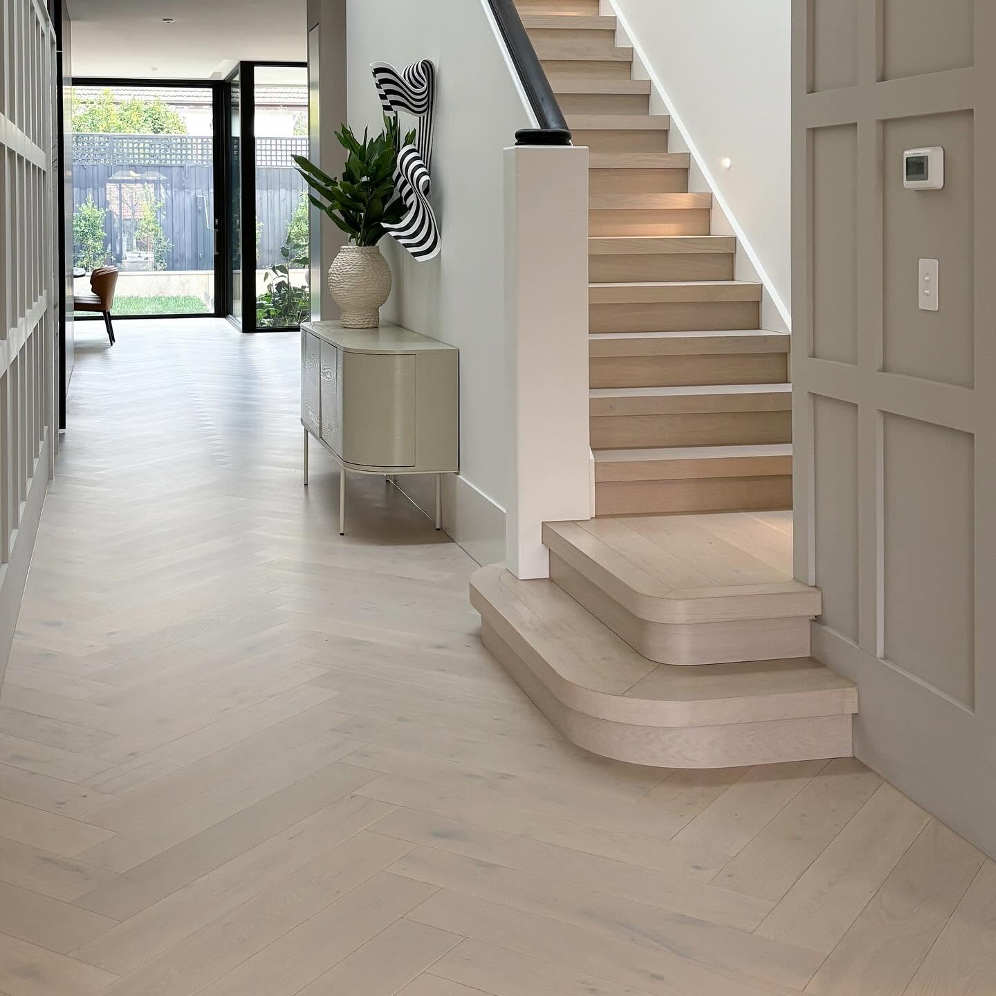 Pale herringbone oak through an entry and staircase